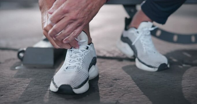 Fitness, hands of person and tie shoes in gym before cardio workout, endurance training or marathon. Closeup, prepare and senior man lace sneakers for morning exercise, wellness or getting ready