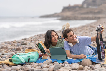 Couple taking selfie while reading on the beach