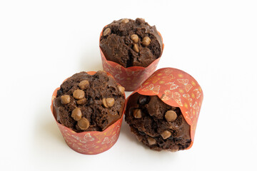 Three chocolate muffin isolated on a white background with copy space. Homemade fluffy and moist chocolate cakes.