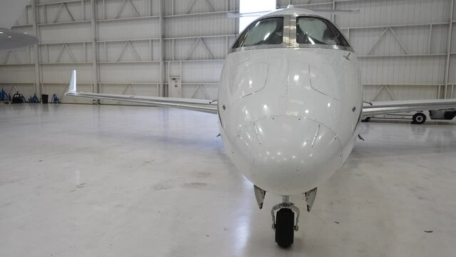 Front view of a white private airplane parked in a hangar.