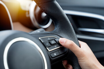 Woman's hand presses the button on the steering wheel of the car close-up.
