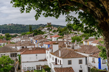 Obraz premium Obidos, Portugal. Cityscape of the town with medieval houses, wall and the Albarra tower. Roofs and castle of Obidos, a medieval town in Portugal