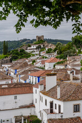 Obidos, Portugal. Cityscape of the town with medieval houses, wall and the Albarra tower. 
Roofs and castle of Obidos, a medieval town in Portugal