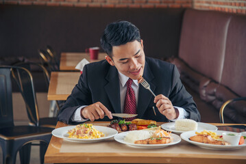 Businessman eat Steak having lunch at a restaurant. Ribs eye steak with mashed potato, salad cream French fries Barbecue Grill and Spaghetti, Happy man sitting have dinner enjoying food