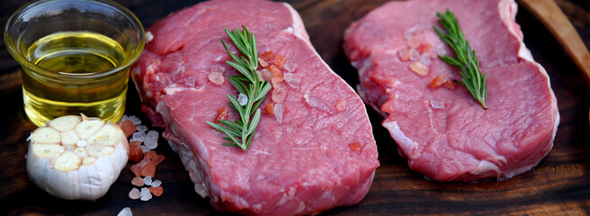 Banner Raw meat beef steak organic fresh ingredient on wooden board table background in kitchen with rosemary, salt, garlic, tomato, olive oil. Meat beef on wooden plate for beefsteak with copy space