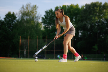 Obraz premium girl hockey player plays field hockey on a sunny day, the hockey player hits the ball with a stick