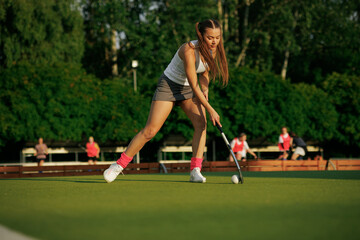 Obraz premium girl hockey player plays field hockey on a sunny day, the hockey player hits the ball with a stick
