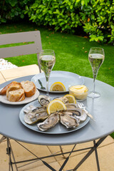 Champagne sparkling wine in glasses and oysters from Arcachon bay served on oysters farm in Gujan-Mestras, with lemon, baquette bread, butter