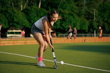 Fototapeta premium girl hockey player plays field hockey on a sunny day, the hockey player hits the ball with a stick