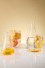 The white table containing some laboratory glassware consist of erlenmeyer flask and beaker, which containing liquid and fresh peach. Photo of front angle, empty space for presentation