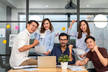 Successful of happy group professional casual business people smiling and laughing to win of celebrating project success.Creative business relaxing and raising hands up in modern office