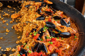 Street food in London, food court on Portobello road Saturday market, fresh prepared colorful paella with rice and sea food big pan, ready to eat