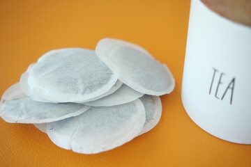 tea bags and a container on a orange color background 