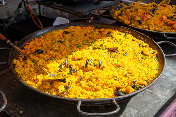Street food in London, food court on Portobello road Saturday market, fresh prepared colorful paella with rice and sea food big pan, ready to eat