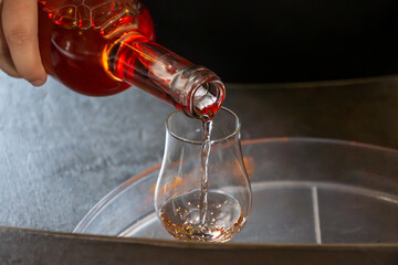 Tasting of cognac spirit aged in old dark French oak barrels in cellar distillery house, Cognac...