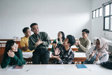 Multicultural Asian teacher and students clapping hands together celebrating successful project in the class.