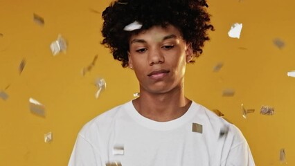 Sad party. Lonely teenager. Birthday melancholy. Disappointed upset guy celebrating holiday alone in golden confetti rain on yellow background.