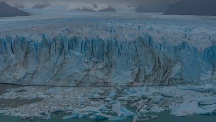 The endless glacier stretches to the horizon between the mountains. A wall of blue ice with cracks,...