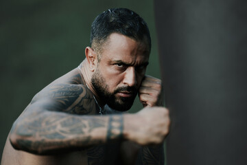 Fist and fight. Man boxing punching bag. Boxing sport. Sportsman workout by punching bag. Boxer punching bag with strong fist. Closeup of danger serious boxer hitting a punching bag.