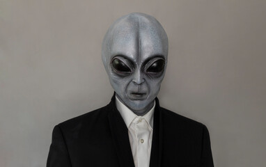 Portrait Of Alien Wearing Suit Gray Background. World UFO Day. Extra Terrestrial Being, Unidentified Flying Objects. Vertical Plane. Grey Humanoid.