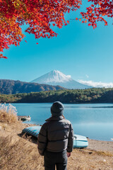 Woman tourist with Fuji Mountain at Lake Saiko in Autumn season, happy Traveler travel Mount Fuji, Yamanashi, Japan. Landmark for tourists attraction. Japan Travel, Destination and Vacation