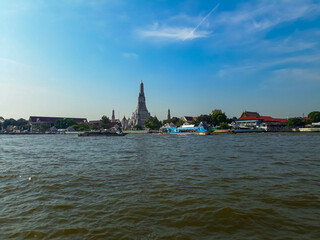 Fototapeta premium Riverside Temple with Traditional Architecture and Boats on the Water