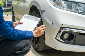 A businessman stands next to his damaged vehicle after an accident, holding a clipboard and examining the scene. An insurance agent arrives to assess the damage and start the claim process.