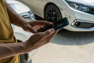 A businessman stands next to his damaged vehicle after an accident, holding a clipboard and examining the scene. An insurance agent arrives to assess the damage and start the claim process.