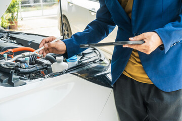 A businessman stands next to his damaged vehicle after an accident, holding a clipboard and examining the scene. An insurance agent arrives to assess the damage and start the claim process.