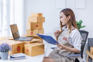 Beautiful Asian online business owner is preparing a parcel box to prepare the package for delivery to the customer asian Entrepreneur SME business concept.