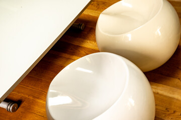 Furniture design: two modern white spherical chairs and a low white coffee table on wooden floor
