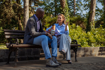 Two people in business clothes having a conversation on a park bench