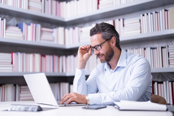 Obraz premium Portrait of teacher with book in library classroom. Handsome teacher in university. Teachers Day. Good school teacher. Tutor at college. Man with books in library. Knowledge and education concept.