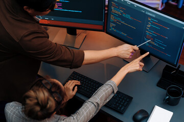 Top view of IT developers discussing with point to intelligent website development coder system...