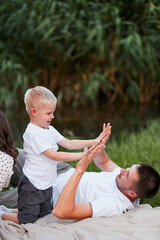 A blond boy claps his dad's hands on a camping trip