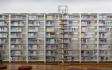 Fototapeta premium Bookcases with ladders in the library. Blur background.