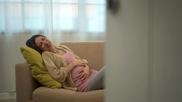 Young pregnant woman suffering from abdominal pain alone at home, female feel abnormal painful contraction during pregnancy, accidental medical urgency case and health care insurance for pregnancy.
