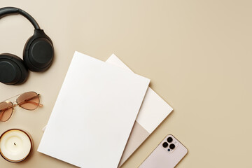 Blank paper, glasses, and wireless headphones on beige background