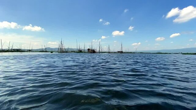 Rawa Pening lake contains water hyacinth plants against a backdrop of mountains and blue sky and white clouds