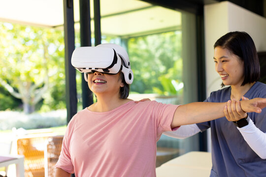 Senior woman using VR headset for physical therapy, guided by female therapist - Powered by Adobe