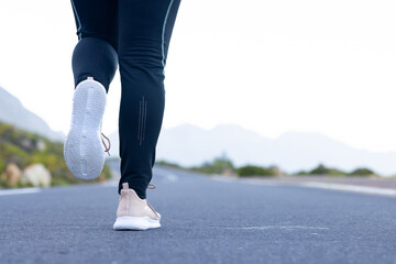 Running on road, person in athletic shoes and leggings during mountain hike, copy space