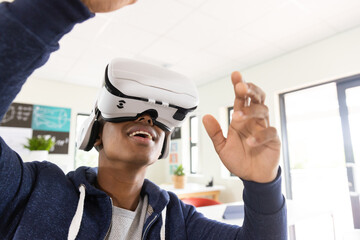 Using VR headset, African American male student experiencing virtual reality in classroom