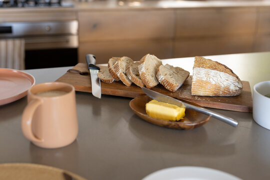 Sliced bread and butter on wooden board with knife in kitchen, copy space