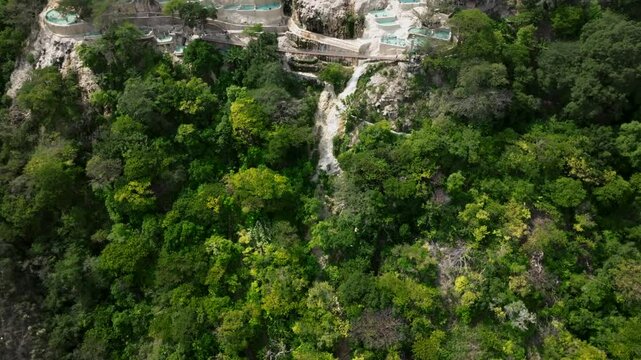 The Grutas Tolantongo resort and hot sping pools are revealed in drone flight over tree canopy