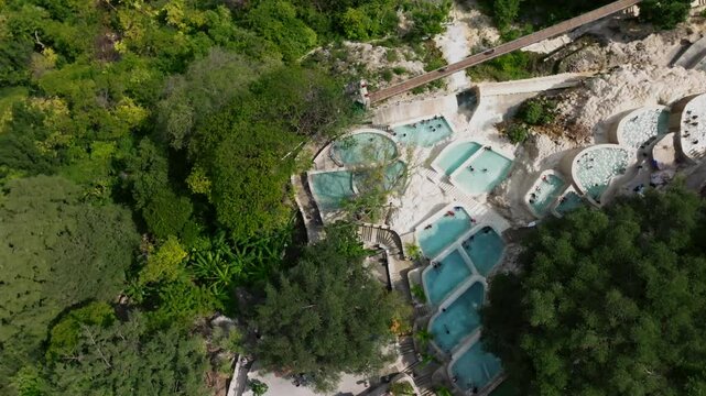Drone flight over the thermal pools at the Grutas de Tolantongo resort, Mexico. Top-down aerial orbit right to left
