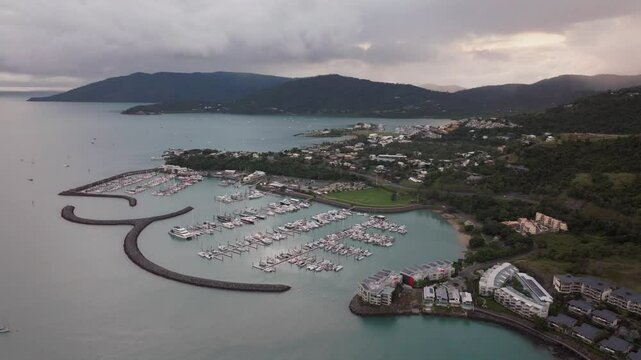 Port Airlie Beach Bay Lagoon Coral Sea marina aerial drone rain clouds mist sunrise morning heart of Great Barrier Reef Whitsundays Whitehaven jetty yachts sailboats buildings backward motion