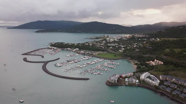 Port Airlie Beach Bay Lagoon Coral Sea marina aerial drone rain clouds mist sunrise morning heart of Great Barrier Reef Whitsundays Whitehaven jetty yachts sailboats buildings circle to the left