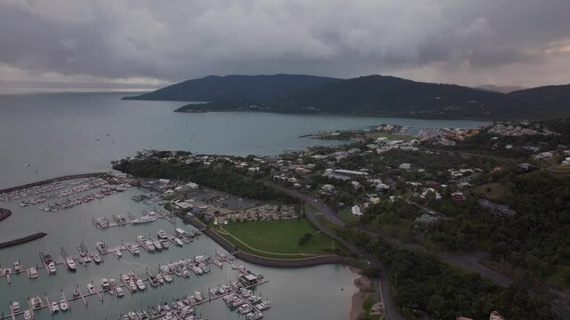 Port Airlie Beach Bay Lagoon Coral Sea marina aerial drone sunrise morning heart of Great Barrier Reef Whitsundays Whitehaven jetty yachts sailboats buildings backwards reveal motion