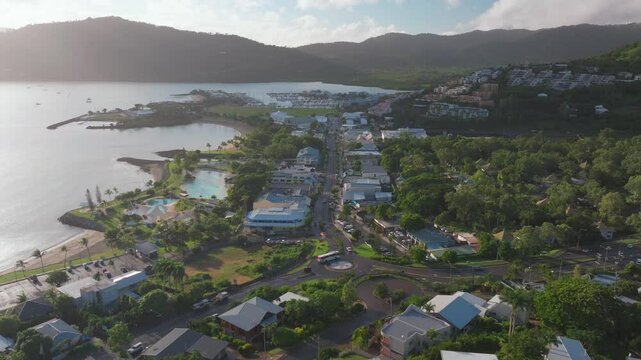 Morning sunrise Airlie Beach Bay Lagoon heart of Great Barrier Reef Whitsundays Whitehaven aerial drone main street cars buildings mist sunny Coral Sea marina jetty sailboats forward reveal motion