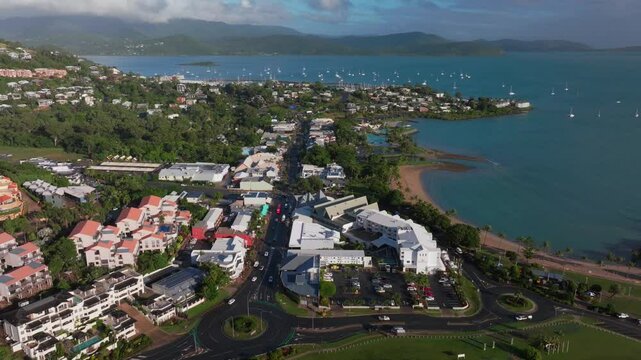 Airlie Beach Bay Lagoon heart of Great Barrier Reef Whitsundays Whitehaven aerial drone main street cars buildings sunrise morning mist sunny Coral Sea marina jetty sailboats forward reveal